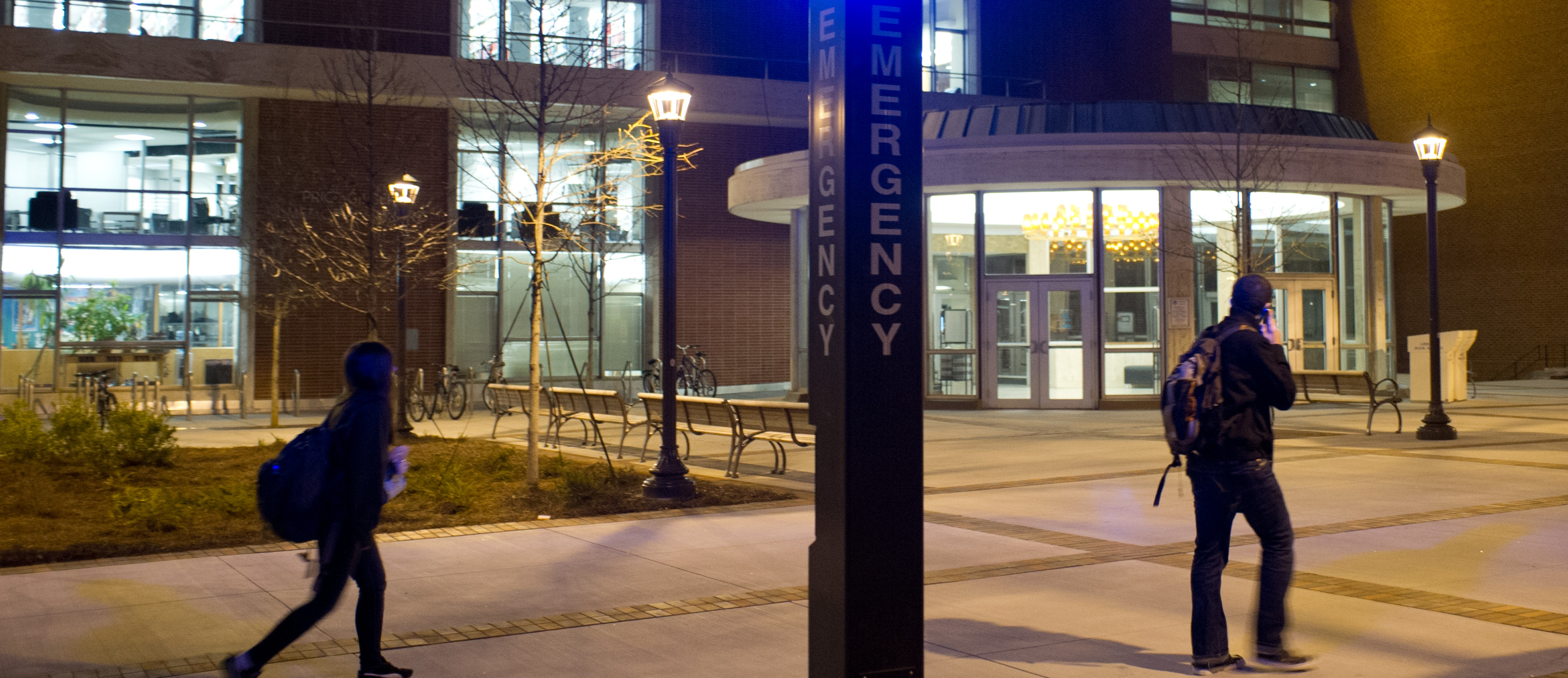 Photo of campus at night featuring an Emergency pole sign.
