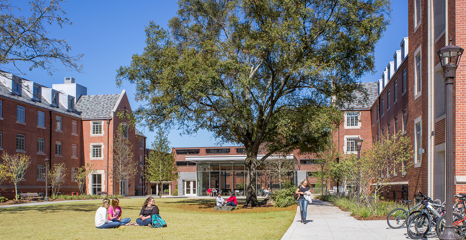 East campus housing with students sitting in the lawan and walking.