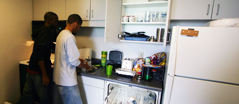 Two young male students cooking in a kitchen.