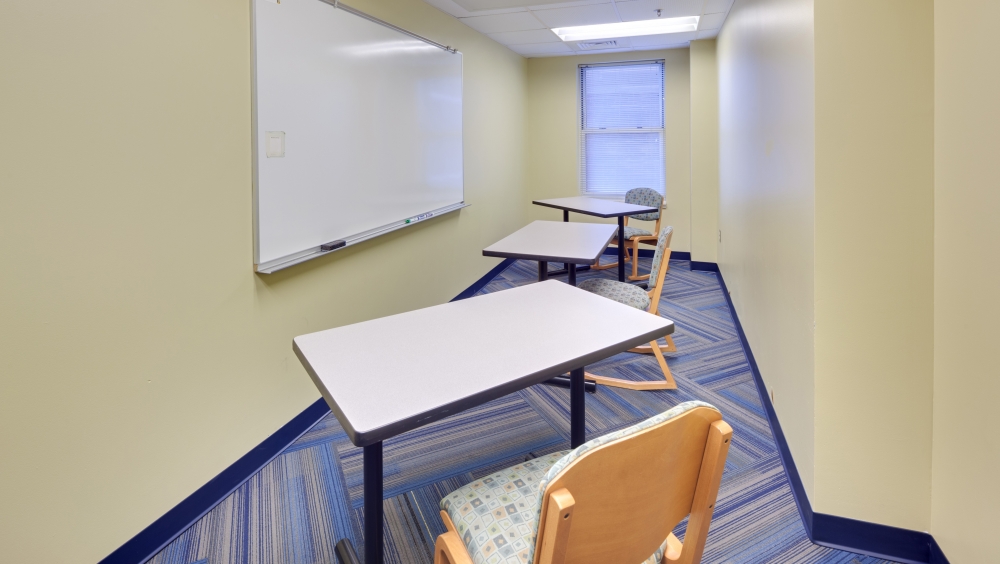 Study room, with desks, chairs and a white board.