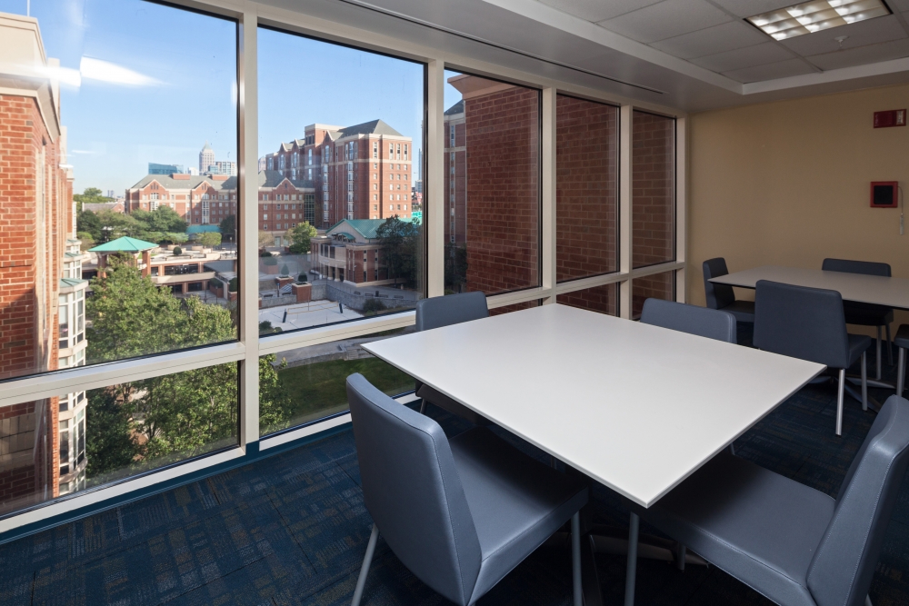 Study furnished with tables and chairs. Floor to ceiling glass panes show the view of other North Ave. Apts. towers.