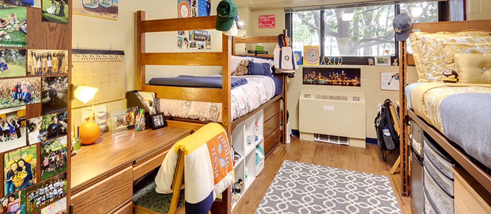 Bedroom with 2 beds high rised, a desk, and a chair. Photos and other student decorations.