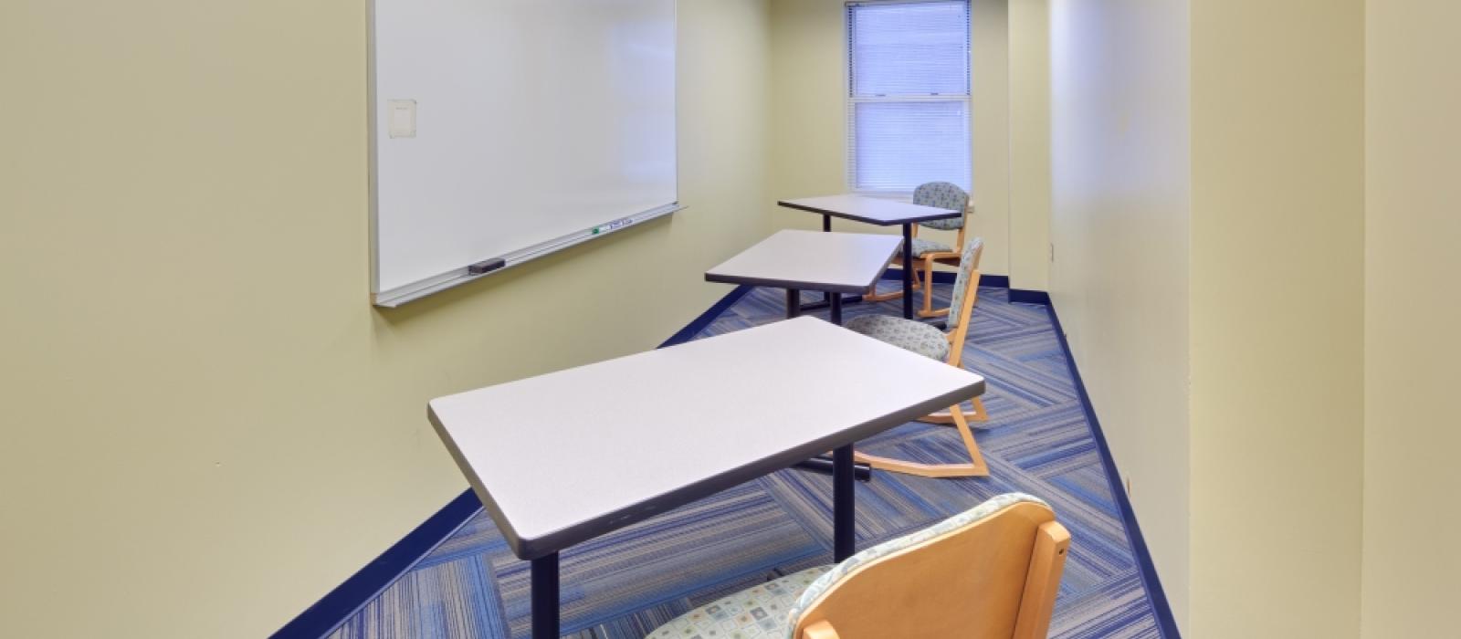 Study room, with desks, chairs and a white board.