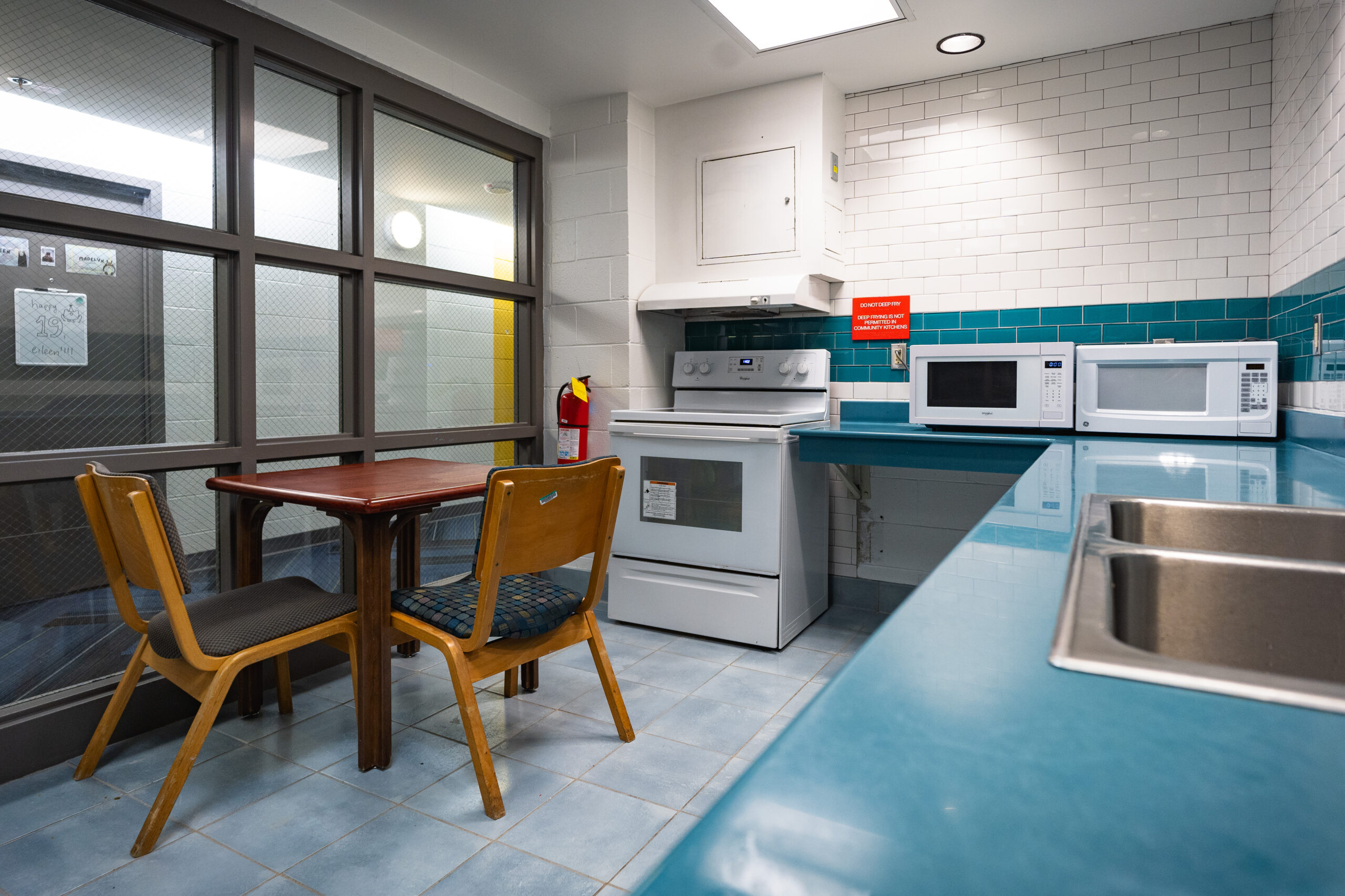 Kitchen with stove, microwave, sink, table and two chairs